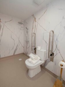 Baño totalmente accesible para personas con movilidad reducida en Casa Cancela, Palas de Rei, diseñado para personas con movilidad reducida, con barras de seguridad, ducha a ras de suelo y amplios espacios de giro.
