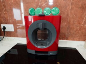 Detalle de cafetera de cápsulas roja con cápsulas de cortesía en la cocina del apartamento de Casa Cancela, Palas de Rei, lista para el uso de los huéspedes.