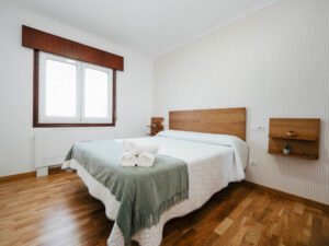 Habitación doble luminosa con suelo de madera y detalles rústicos en Casa Cancela, Palas de Rei, ideal para el descanso en el Camino de Santiago.
