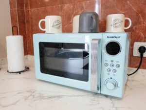 Detalle de microondas de diseño retro color azul y tazas de café sobre la encimera de mármol en el apartamento de Casa Cancela, Palas de Rei.