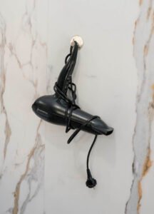 Equipamiento del baño en Casa Cancela: secador de pelo disponible para los huéspedes, ubicado sobre una moderna pared de mármol blanco en Palas de Rei.