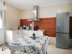 Vista de la zona de comedor con mesa vestida y cocina integral al fondo en el apartamento de Casa Cancela, Palas de Rei; un espacio luminoso y cómodo para grupos y familias.